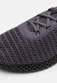 Fialové síťované tenisky s texturovaným povrchem a zesílenou podrážkou, s kontrastními černými detaily a tradičním šněrováním.