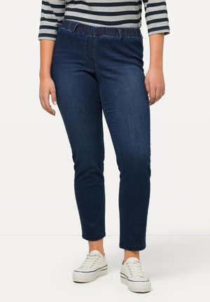 Jeans in denim blu scuro con vita arricciata, lunghezza cropped e vestibilità slim. Abbinati a sneakers bianche per un look informale.