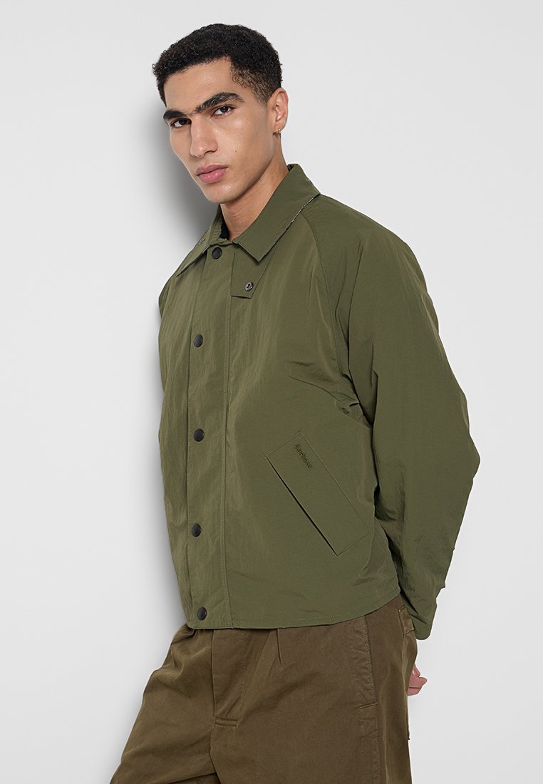Olijfgroene lichtgewicht jas met een kraag, zwarte knoopsluitingen, zijzakken en een soepele textuur. Geschikt voor casual gebruik.