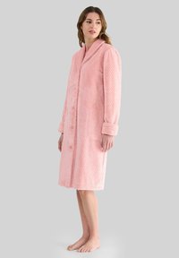 Bata de baño rosa hecha de tela texturizada, con cuello de chal, mangas largas, cierre de botones y dos bolsillos frontales.