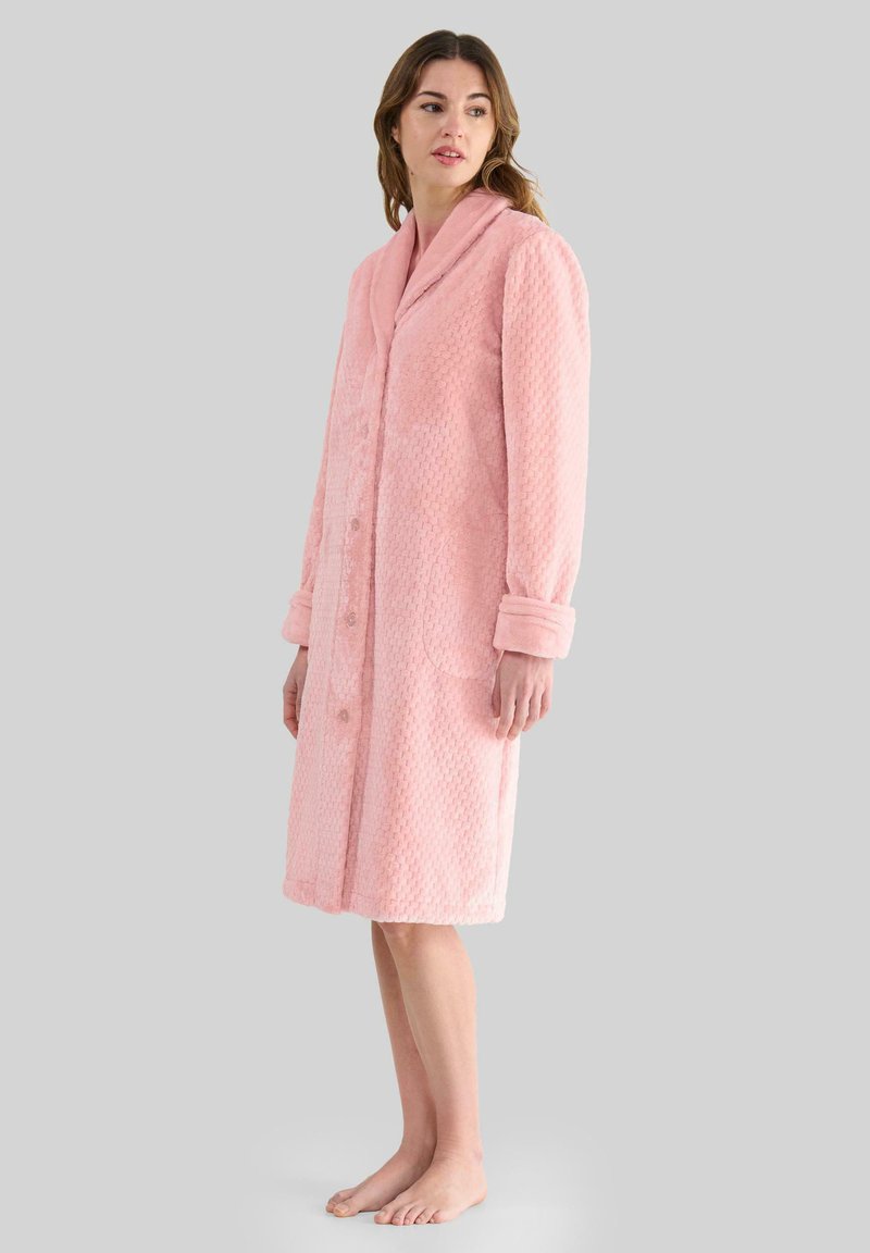 Bata de baño rosa hecha de tela texturizada, con cuello de chal, mangas largas, cierre de botones y dos bolsillos frontales.