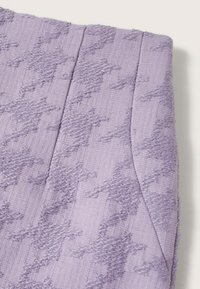 Tissu lavande avec motif pied-de-poule en relief texturé et couture verticale visible sur une surface lisse.