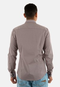 Chemise à manches longues avec un motif géométrique multicolore, fabriquée en tissu léger, dotée de poignets à boutons et d'une coupe ajustée.