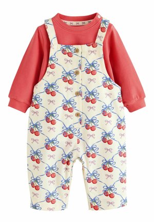 T-shirt bébé à manches longues corail rose sous une salopette crème avec motif cerises rouges et ruban bleu, boutons en bois devant.