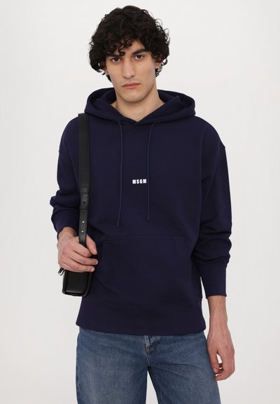 Navy blue hoodie with a front pocket and white "MSGM" logo. Features drawstrings, relaxed fit, and is paired with light blue jeans.