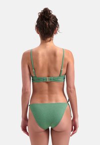 Zielony dwuczęściowy bikini z cienkimi ramiączkami, regulowanymi bokami i fakturowanym wykończeniem. Plecy posiadają zapięcie i minimalne zasłonięcie.