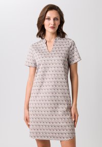 Robe à manches courtes avec col en V, présentant un motif géométrique crème sur fond marron clair, fabriquée en tissu lisse.