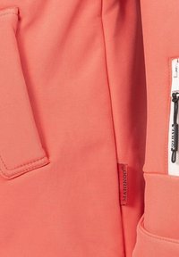 Korallfärgad tyg med en slät textur, med en sidoficka, en vit dragkedja och en märkestagg. Enkel och funktionell design.