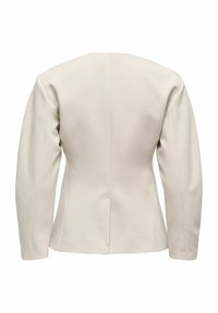 Pielāgota bēša žakete ar strukturētu dizainu, gariem piedurknēm un gludu auduma faktūru. Ir redzama aizmugurējā šuve un minimālistiska silueta forma.