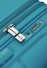Valigia rigida turchese con doppia zip e lucchetto a combinazione, dotata di una superficie testurizzata per una maggiore durata e un punto di accesso sicuro.