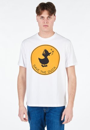 T-shirt bianco in cotone con una grafica rotonda arancione raffigurante un'anatra nera e la scritta "SALVA L'ANATRA", maniche corte e scollatura rotonda.