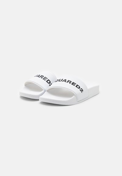 Vita slide-sandaler med en bred rem med "SQUARED2" i fet svart text. Strukturad sula och slätt ovandelmaterial.