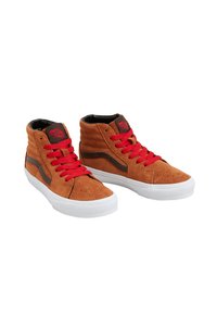 Baskets montantes en daim brun avec des lacets rouges, semelles en caoutchouc blanc et intérieur noir, dotées d'un logo sur le côté et d'accents cousus.