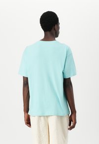 Light blue cotton t-shirt with a relaxed fit, short sleeves, and a crew neck. The texture appears soft and smooth, with minimal detailing.