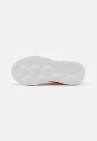 Suela de zapato de goma blanca con patrones de tracción circulares y bordes texturizados. Presenta un logo en relieve y zonas de amortiguación distintas.