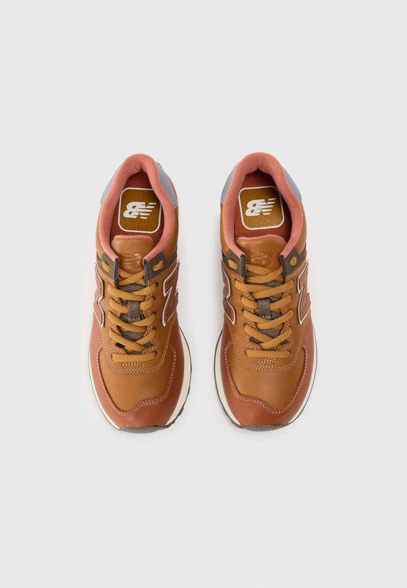Brune lædersneakers med beige accenter, grå hældetalje og teksturerede snørebånd. Indersålen viser New Balance-logoet.