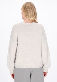 Jasnoszary sweter dziany o luźnym kroju, z prążkowanymi mankietami i okrągłym dekoltem. Miękka tekstura, prosty design, brak widocznych wzorów lub ozdób.