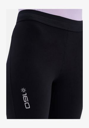 Schwarze Sportleggings aus dehnbarem Material, mit einer glatten Textur und einem dezenten silbernen Logo an der Seite.