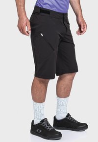 Schwarze Shorts aus leichtem Material, mit einer seitlichen Reißverschlusstasche, flachem Vorderteil, knielang und einem Klettverschluss an der Taille.
