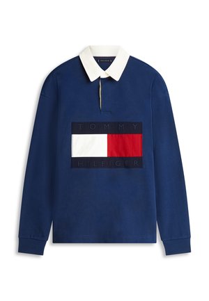 Polo de manga larga azul marino con cuello blanco y gran parche con el logo de Tommy Hilfiger en rojo, blanco y azul marino en el pecho.