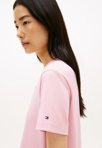 Ροζ βαμβακερό μπλουζάκι με κοντά μανίκια, με στρογγυλή λαιμόκοψη και μικρό κεντητό λογότυπο στο αριστερό μανίκι. Ομαλή υφή.