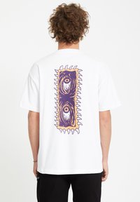 Hvid bomulds t-shirt med et farverigt grafisk design på ryggen, der har et abstrakt mønster og takkede kanter.