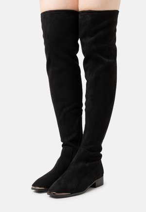 Black over-the-knee boots made of suede. Features a smooth texture, pointed toe, and a low block heel with a metallic accent at the toe.