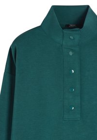 Turkusowy sweter z wysokim kołnierzem, z pięcioma błyszczącymi guzikami z przodu. Wykonany z miękkiego materiału o teksturowanym wykończeniu.