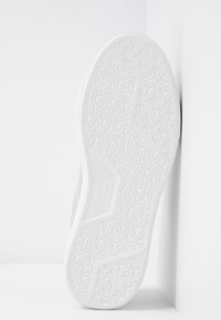 Semelle de chaussure en caoutchouc blanc avec un motif texturé ; bords incurvés et design angulé. Transition douce vers un matériau supérieur gris pâle.