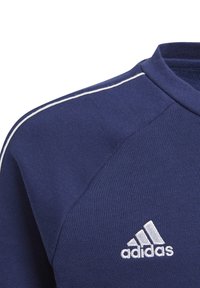 Maglietta sportiva blu navy in tessuto strutturato, con piping bianco lungo la cucitura della spalla e logo Adidas bianco ricamato.