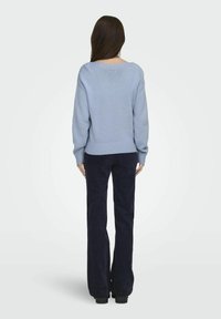 Light blue knit sweater with a wide neckline and ribbed cuffs, paired with dark navy corduroy pants. Smooth texture, loose fit, and casual design.