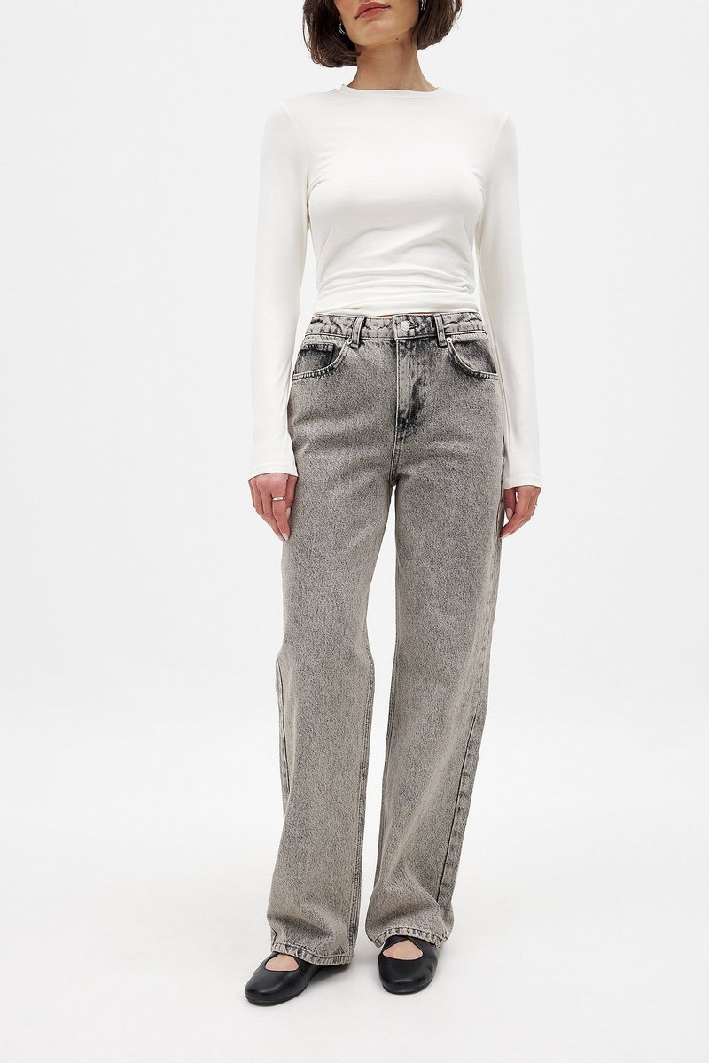 Valkoinen pitkähihainen paita yhdistettynä harmaisiin korkeavyötäröisiin farkkuihin, joissa on haalistunut pesu ja suora lahje, ja asusteena mustat ballerinat.