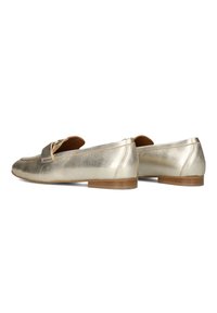 Metalen gouden loafers met een gladde textuur, ronde neus, een klein hakje en decoratieve vetersluiting aan de voorkant. Bruine binnenzolen zichtbaar.