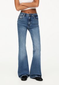 Urtavlade blå denimjeans med hög midja, stickade fickor och en slät yta. Har en knapp- och dragkedjeslutning.