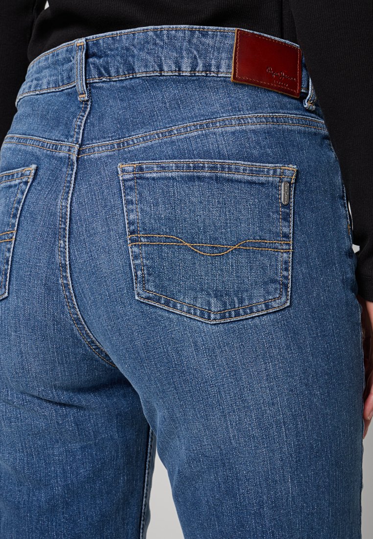 Jean en denim bleu au design ajusté, avec une taille haute, des coutures contrastantes, une étiquette en cuir et deux poches arrière.