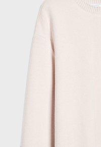 Jasnoróżowy sweter z dzianiny o prążkowanej strukturze, okrągłym dekolcie i obniżonym szwie ramion. Miękka tkanina, prezentująca prosty fason.