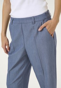 Pantaloni su misura blu con una texture liscia, dotati di frontale piatto, tasche laterali e passanti per cintura. Il tessuto presenta un motivo fine e sottile.