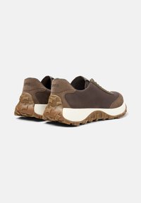 Braune Sneakers mit einem strukturierten Design, ausgestattet mit einer weißen Zwischensohle und einer tiefen Profilsohle. Die Ansicht zeigt die Rückseiten der Schuhe.