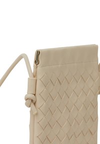 Beige läderclutch med flätat mönster, vikbar topp och avtagbar rem. Har ett metallspänne för säker stängning.