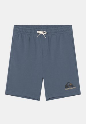Niebieskie szorty z elastycznym pasem, białym sznurkiem do regulacji i kieszeniami po bokach, z czarno-brązowym logo Quiksilver na lewym mankiecie nogawki.