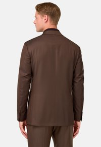 Brauns uzvalks ar gludu tekstūru, strukturētu dizainu, vienu aizmugurējo venti un pogājamām piedurknēm. Pielāgotā piegriezuma dēļ siluets ir uzlabots.