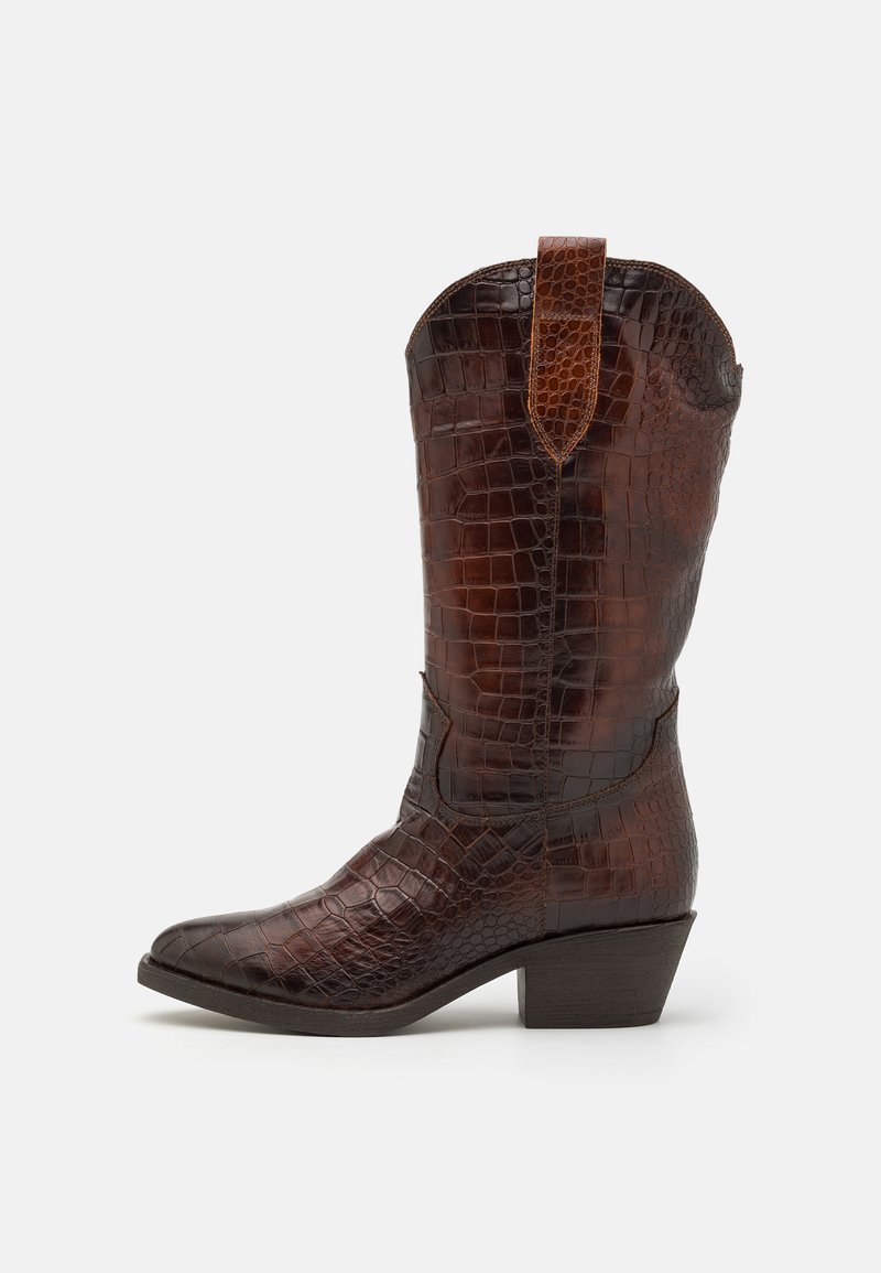 Bota vaquera marrón con textura de cocodrilo, punta afilada, tacón bajo de altura media y una etiqueta decorativa en la parte superior.