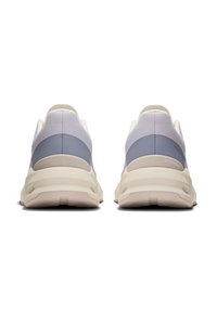 Back view of sports shoes in light purple and cream. Mesh upper with rounded heel and cushioned sole, featuring recessed circular details.