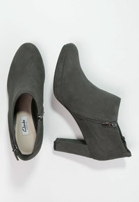 Grå mockaankelboots med hög klack, sidodragkedjor och smal klack. Mjuk yta med en ren design och minimalistisk märkning.