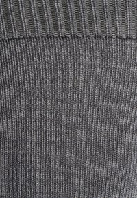 Tessuto lavorato a maglia grigio con texture a coste orizzontali, che mostra un motivo uniforme e un aspetto morbido.