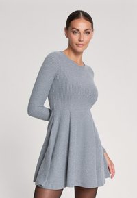 Abito grigio a coste con maniche lunghe, scollatura arrotondata, gonna svasata e un tessuto testurizzato che migliora l'elasticità e il comfort.