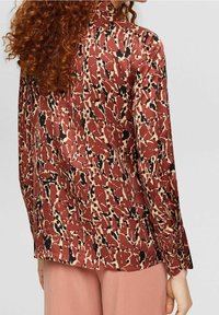 Blusa con motivo rosso e beige, dalla texture liscia, con maniche lunghe e colletto; presenta un design astratto vario.