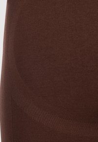 Sedia imbottita marrone con una finitura liscia e una texture a coste. Forma contornata progettata per un supporto ergonomico, che mette in evidenza linee eleganti.