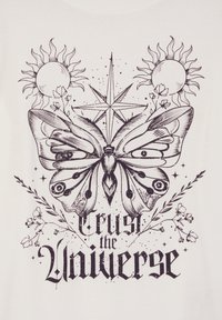 Biała koszulka z czarnym wzorem graficznym przedstawiającym motyla, motywy słońca, gwiazdę, elementy kwiatowe oraz tekst "Zaufaj Wszechświatowi".