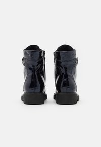 Bottes chelsea en cuir verni noir avec une texture crocodile, dotées d'une fermeture éclair et d'une semelle en caoutchouc noir solide.